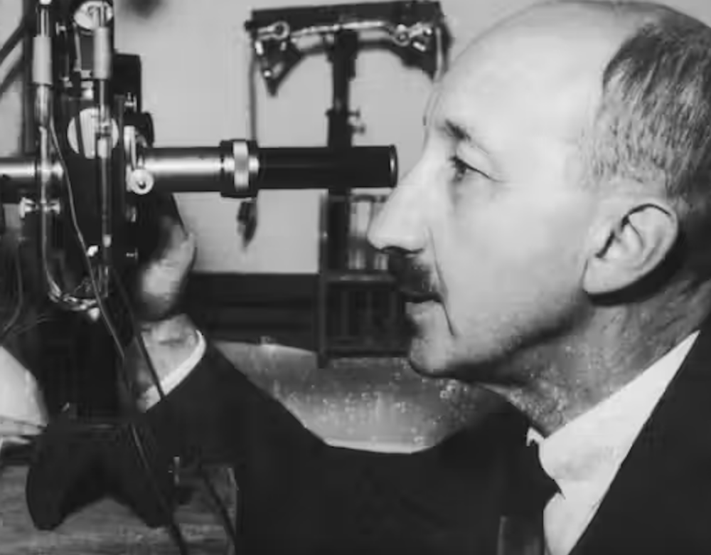 Black and white image of man looking into microscope